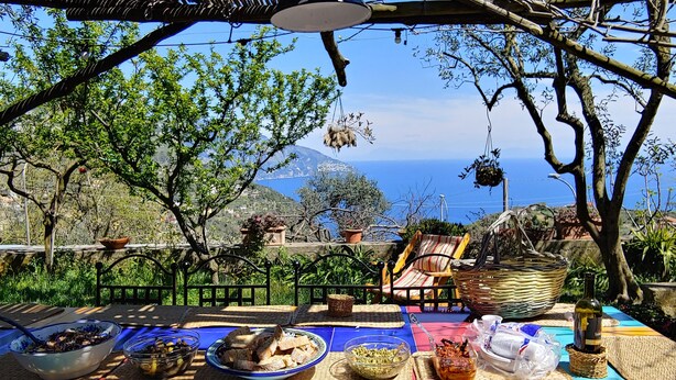 Eine Terrasse mit gedecktem Tisch, mit Blick auf eine malerische Küstenlandschaft.