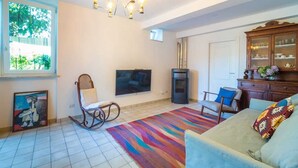 Ein Wohnzimmer mit Fernseher, Kamin, Schaukelstuhl und einem farbenfrohen Teppich.
