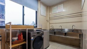 Habitació d'hotel senzilla amb rentadora, un rentapla i finestra que ofereix vista a la ciutat.