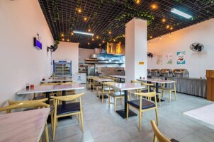 A restaurant interior with tables and chairs, a kitchen area, and a counter.