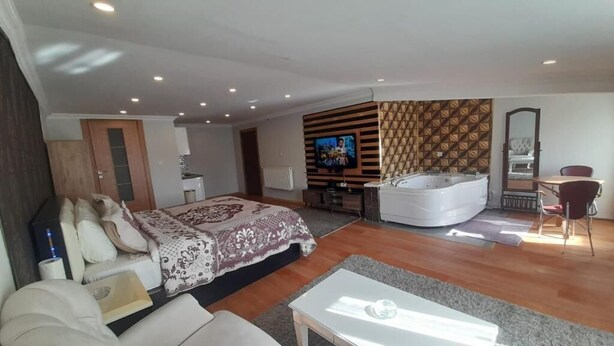 Ein modernes Schlafzimmer mit einem großen Bett, einem Fernseher, einer Badewanne und einem Essbereich.