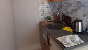 Eine kleine Küche mit Spüle, Arbeitsplatte und Holzschränken.