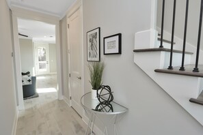 Ein Flur mit einem Glastisch, einer Zimmerpflanze und zwei gerahmten Bildern an der Wand.