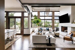 Una sala de estar moderna con un ventanal grande, una chimenea y un televisor de pantalla plana.