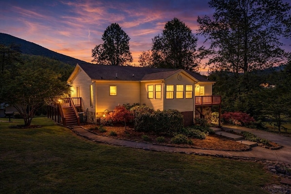A two-story house with a front porch, a covered deck, and a well-maintained lawn.