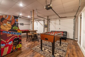 Une pièce équipée d’un baby-foot, ornée d’une grande fresque murale et comprenant un espace bar.