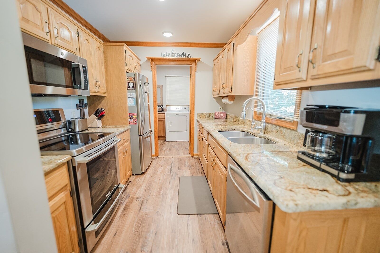 A compact kitchen with wooden cabinets, stainless steel appliances, and a marble countertop.