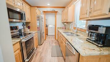 A compact kitchen with wooden cabinets, stainless steel appliances, and a marble countertop.