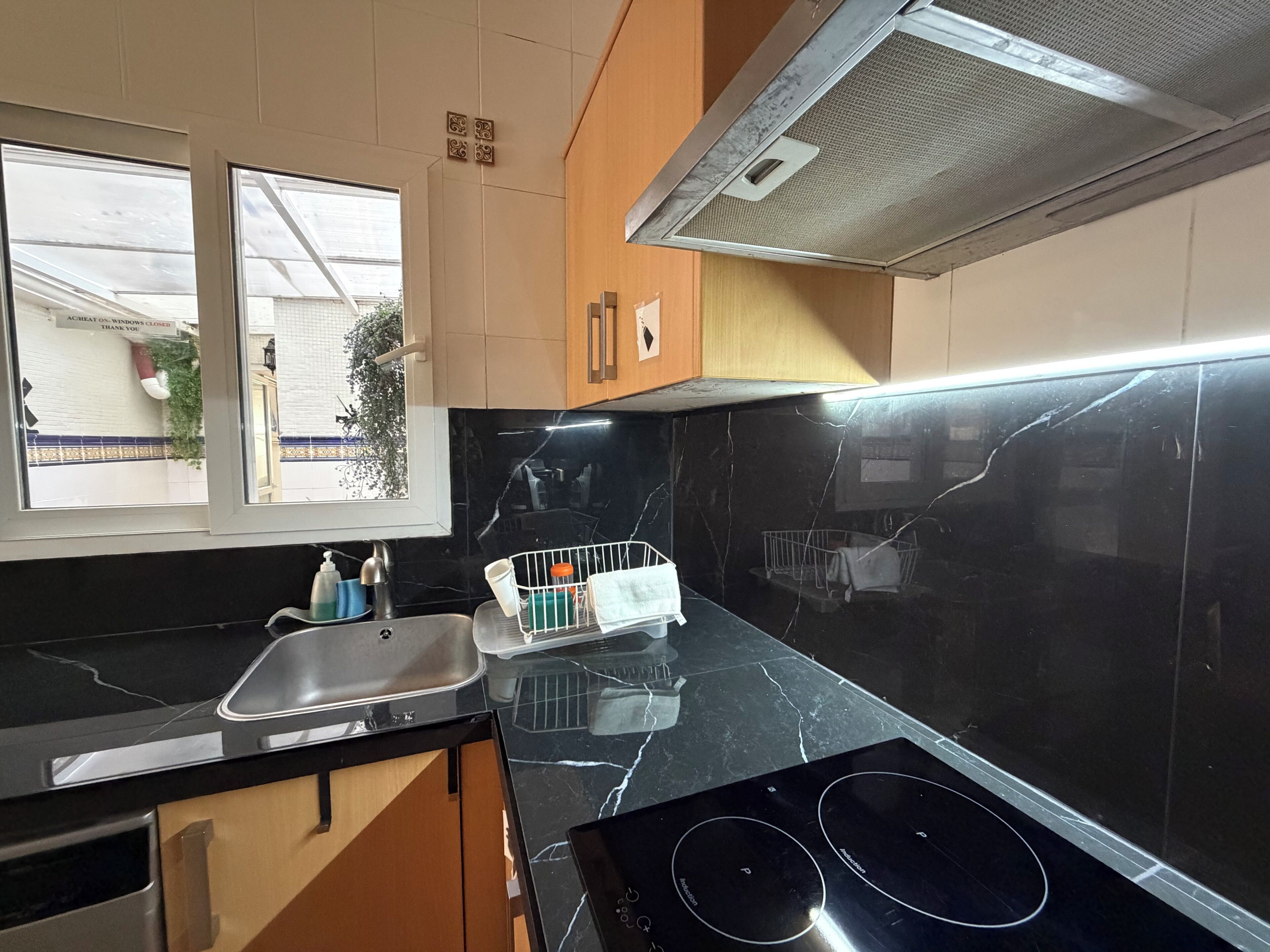 A kitchen with a black countertop, stainless steel sink, and a stove.