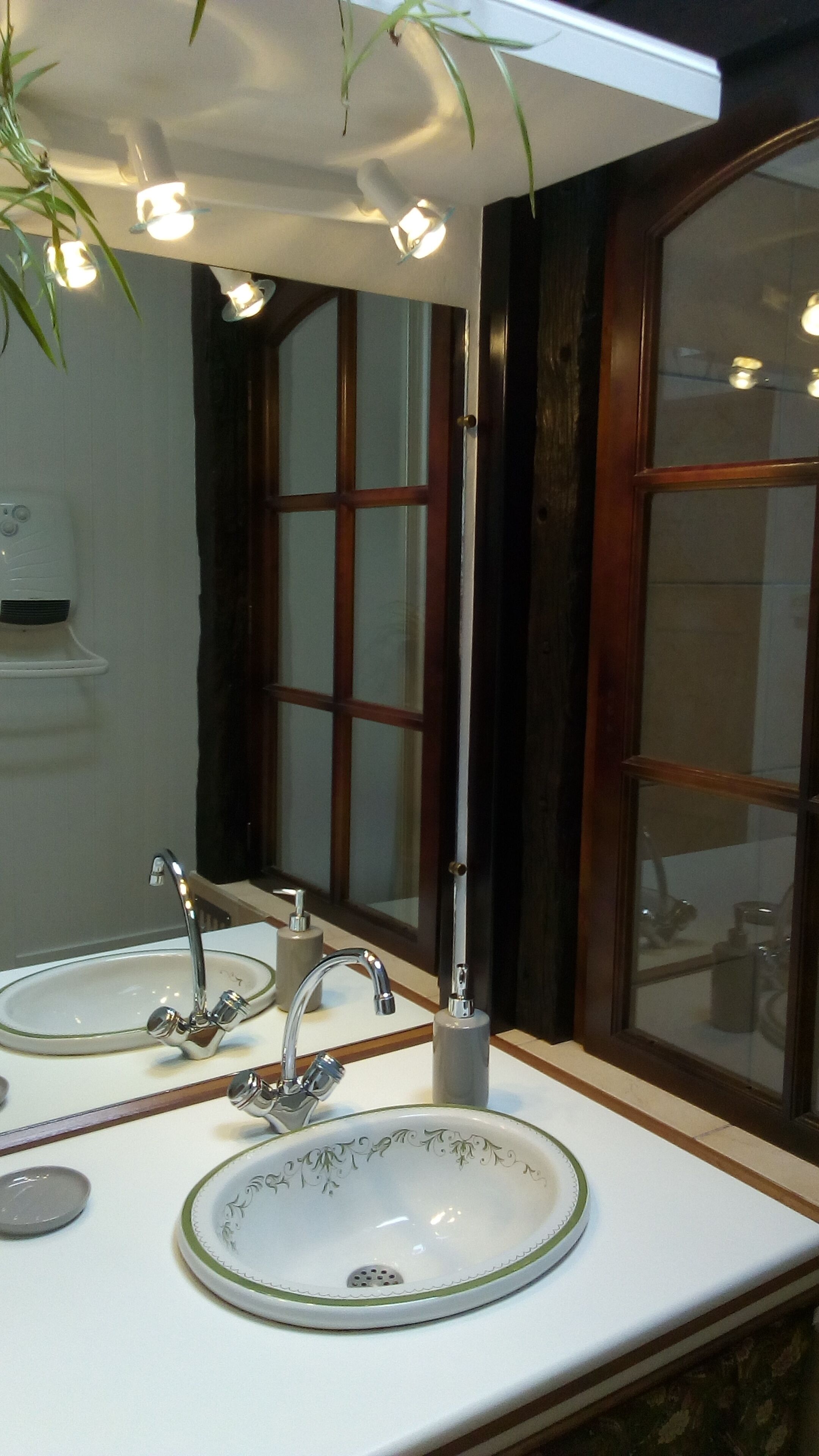 Een badkamer met twee wastafels, een spiegel en een raam met houten kozijnen.