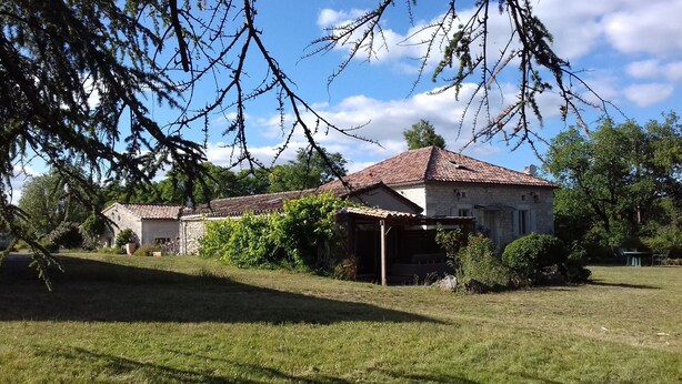 A rustic stone building with a tiled roof, surrounded by lush greenery and trees. - Charming Gîte (4 people) ideal for couples or families, near Montcuq
 (PORTE DU QUERCY)