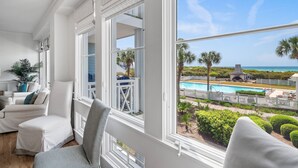 A room with large windows overlooking a pool and a view of the ocean.