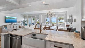A modern kitchen with a large island, built-in dishwasher, and a view of the ocean.