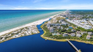 An aerial view of a coastal area with a beach, a marina, and residential buildings.