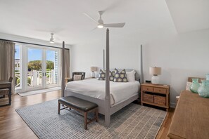Relax in a serene bedroom with a four-poster bed, ceiling fan, and expansive window offering a view of the outdoors.