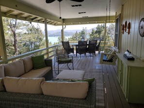 A covered porch with a wicker sofa, dining table, chairs, and a swing. - Sailaway!- Huge Lake Views; Easy Walk to Shoreline! Boat Launch Nearby; Pool! (Garfield)