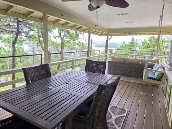 A covered outdoor area with a table and chairs, a hanging fan, and a view of trees and hills. - Sailaway!- Huge Lake Views; Easy Walk to Shoreline! Boat Launch Nearby; Pool! (Garfield)