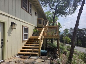A two-story house with a wooden staircase leading to a deck.