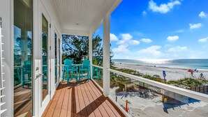 A wooden deck with glass doors and a view of the beach.