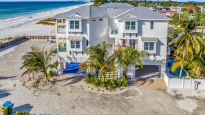 A beachfront property with a two-story building, a swimming pool, and a beach view.