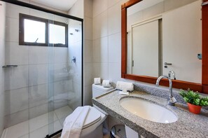 A modern bathroom with a glass shower enclosure, a white toilet, a granite sink with a mirror above, and a potted plant on the countertop. - VG Sun Cumbuco Pé Na Areia Bangalô 6 Pessoas By DM Apartments (Caucaia)