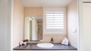 Un baño con lavamanos, espejo y ventana.