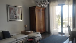 Ein Wohnzimmer mit einer Couch, einem Schrank, einer Pendelleuchte und einem Essbereich mit Stühlen und einem Tisch.