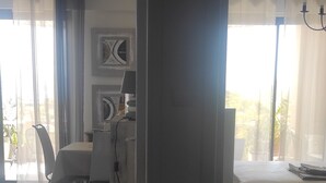 Ein modernes Wohnzimmer mit Essbereich, großen Fenstern und leichten Vorhängen, mit Blick ins Freie.