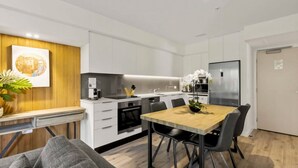 Een moderne keuken met witte kasten, een houten eettafel en zwarte stoelen.