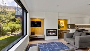 Een moderne woonkamer met een open haard, een televisie en een keukenhoek.