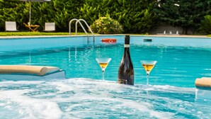 A swimming pool with lounge chairs and a bottle of champagne.