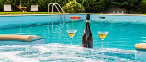 A swimming pool with lounge chairs and a bottle of champagne.