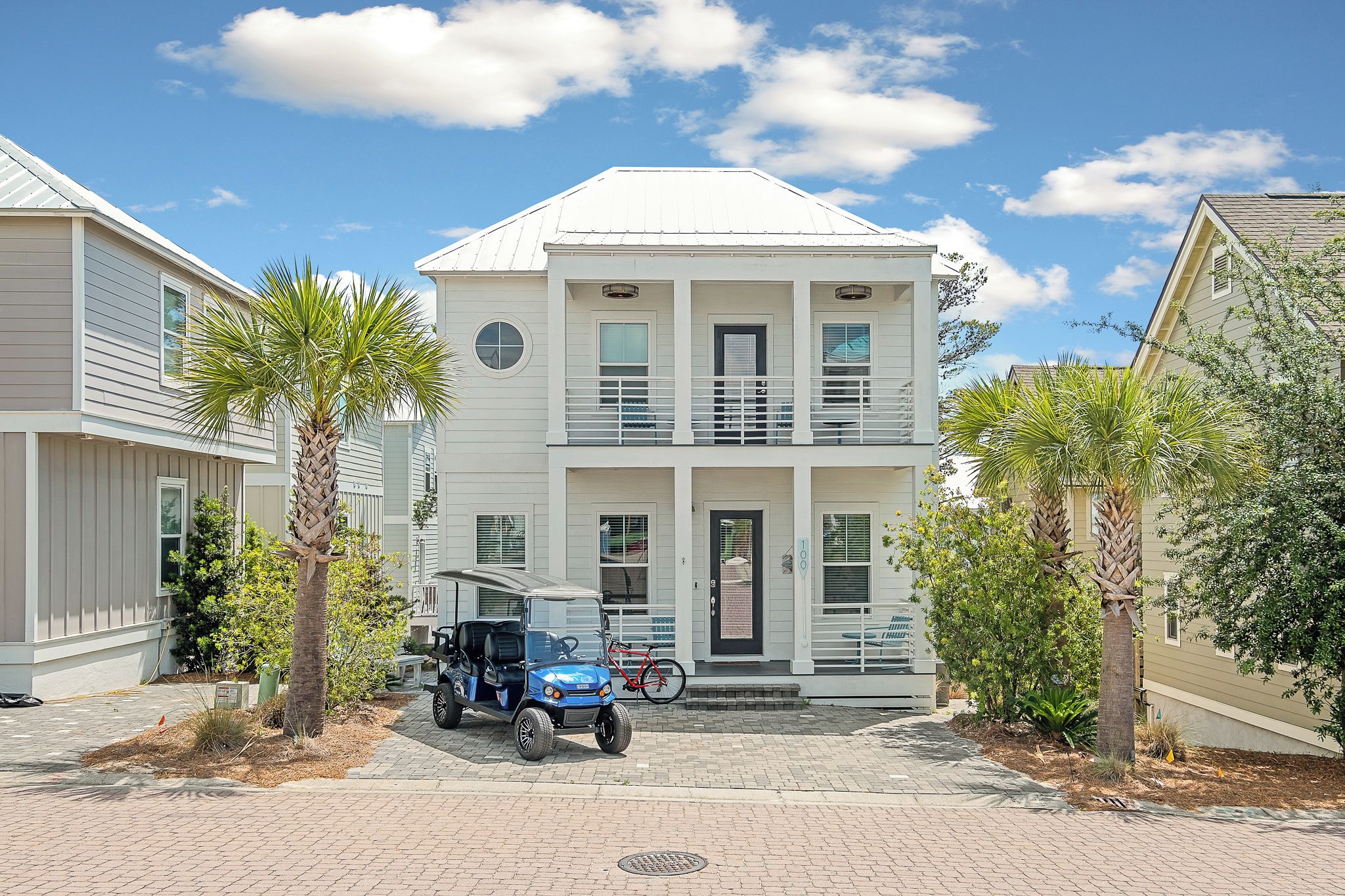 A two-story house with a balcony, a parked blue vehicle, and a bicycle.