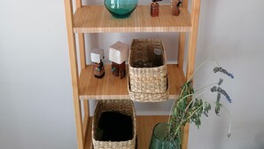 En træhylde med forskellige genstande, heriblandt en potteplante, en skål i glas og dekorative objekter.
