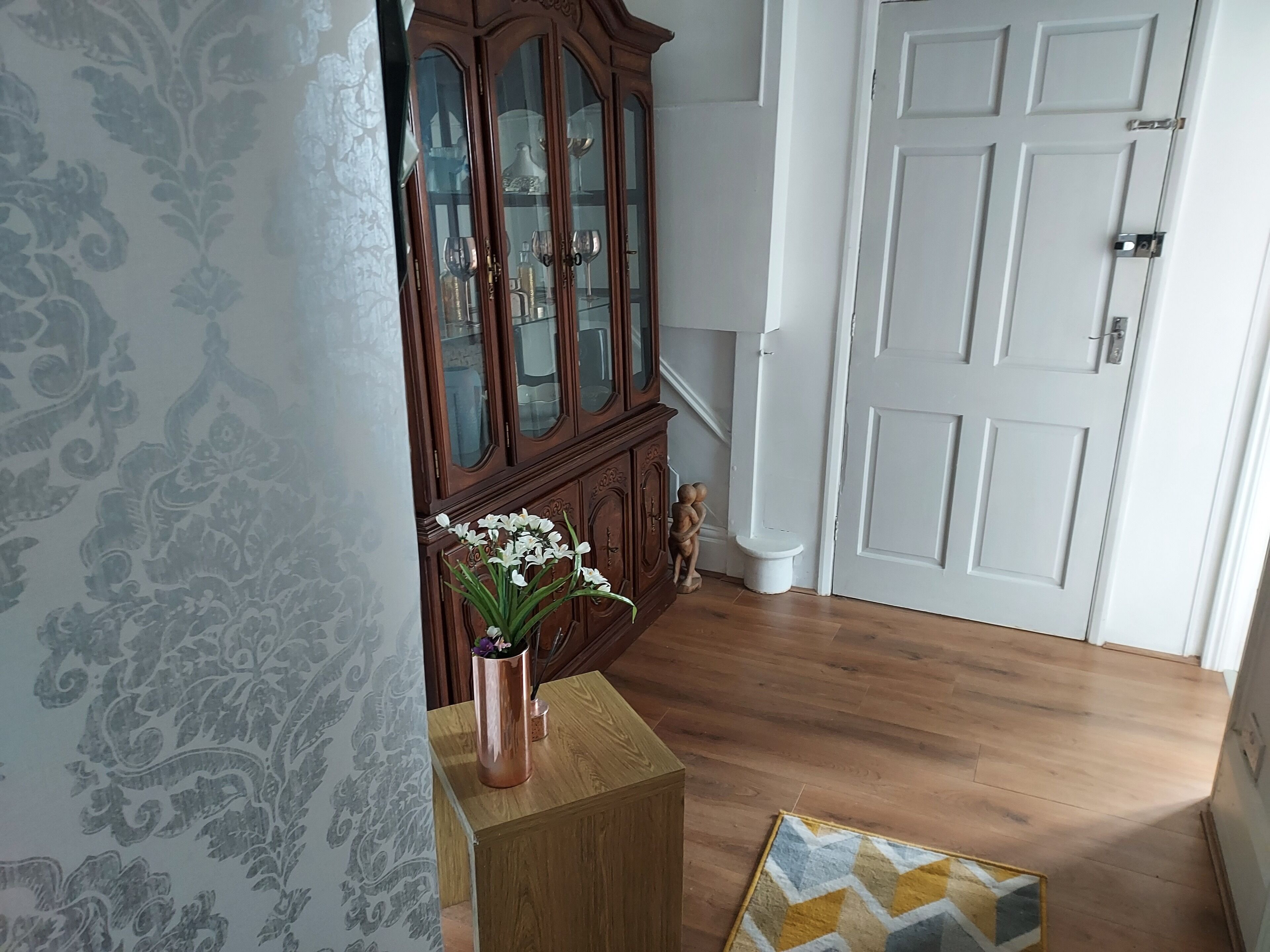 A room with a wooden cabinet, a white door, and a patterned wall.