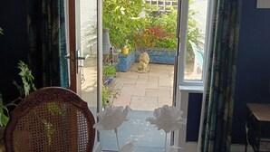 An open door leading to a garden with a variety of plants and a cat sitting on the ground. - Morecambe Apartment - Sleeps 3 - 5 Mins to Sea (Morecambe)