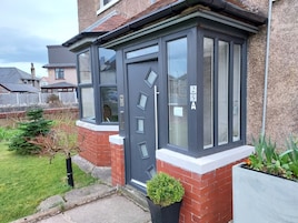 A modern house with a dark grey door, numbered 25A, and a bay window.