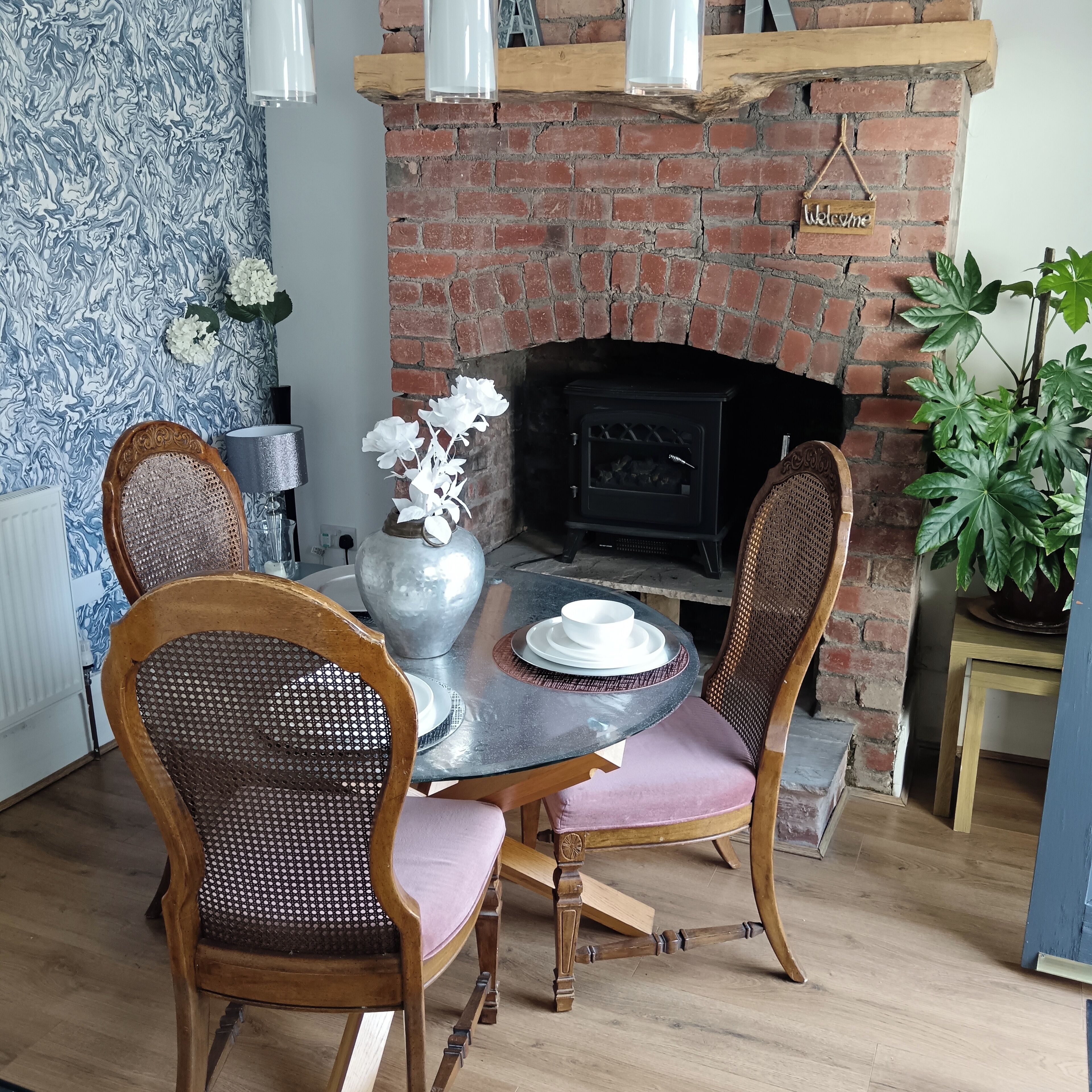 A dining area with a brick fireplace, a round table, and four chairs.