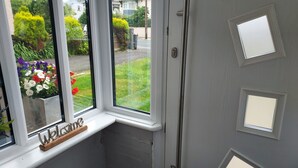 A door with a window, a welcome sign, and a view of a garden. - Morecambe Apartment - Sleeps 3 - 5 Mins to Sea (Morecambe)