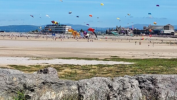 A beach with people flying kites and a building in the background. - Morecambe Apartment - Sleeps 3 - 5 Mins to Sea (Morecambe)