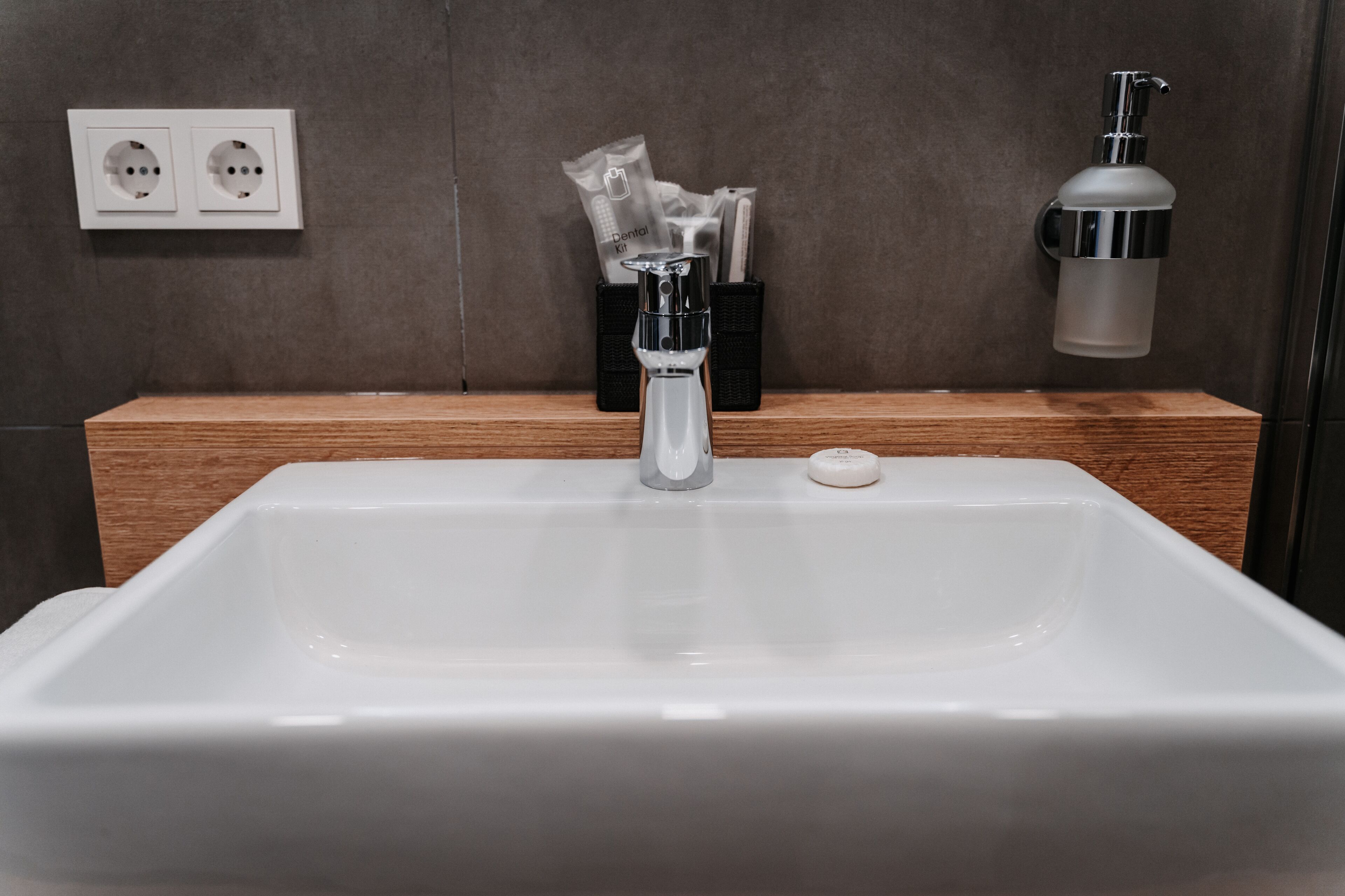 A modern bathroom with a white sink, a toothbrush holder with dental items, and a soap dispenser.