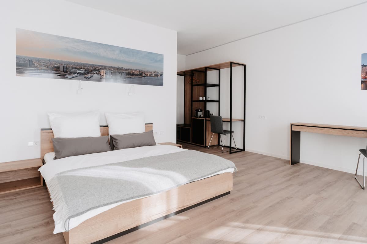 A modern bedroom with a bed, a desk, and a bookshelf.