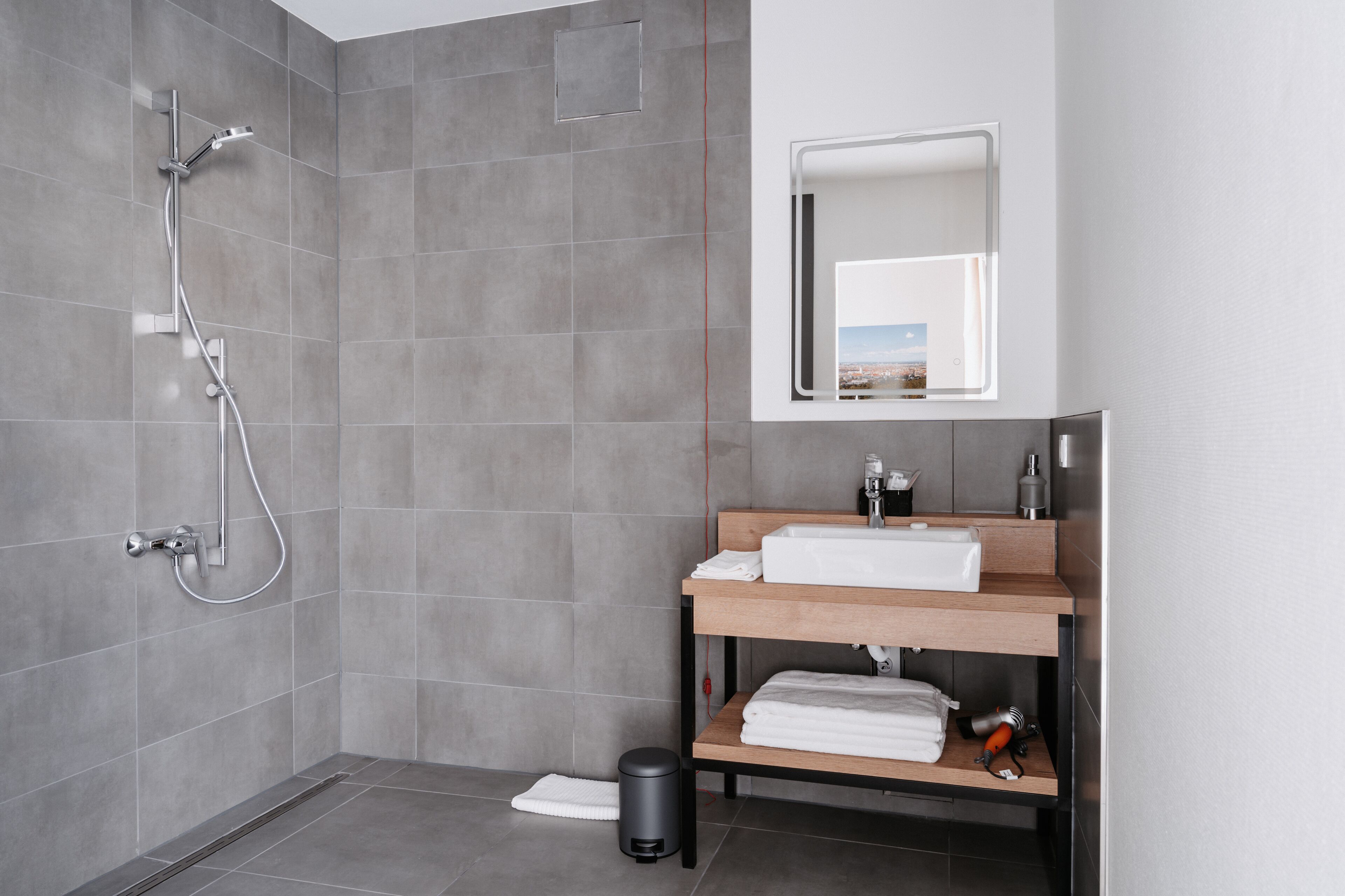 A modern bathroom with a shower, a sink with a mirror, and a towel rack.