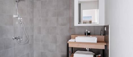 A modern bathroom with a shower, a sink with a mirror, and a towel rack.