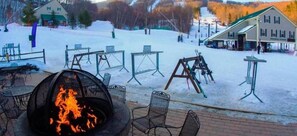 Relax by the fire pit in a mountain resort setting, surrounded by comfortable seating and breathtaking views.