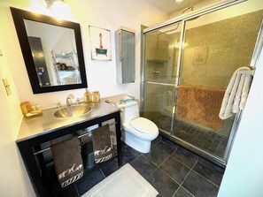 Een moderne badkamer met een grote spiegel, een wastafel, een toilet en een douche met glazen wanden.