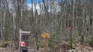 A welcome sign with a flag, a wooden signpost, and a red sign with the number 531.