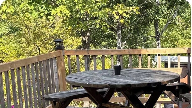 A wooden deck with a picnic table and benches.