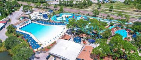 An aerial view of a resort with multiple swimming pools, a large central pool, and surrounding amenities.