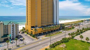 Ein Hochhaus-Hotel mit mehreren Etagen, einem Parkplatz und Blick auf den Strand.